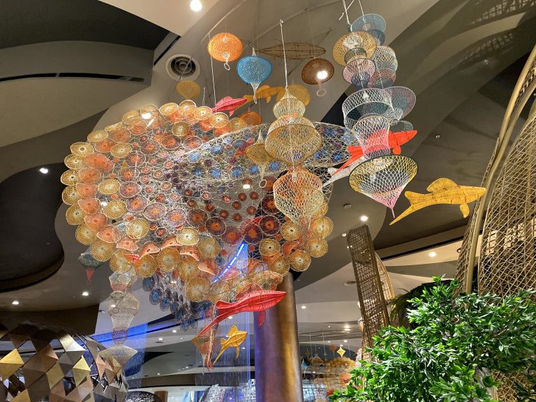 Hanging colorful objects in ceiling and the purpose is for decoration. Some of them are circles and in a fish shape.