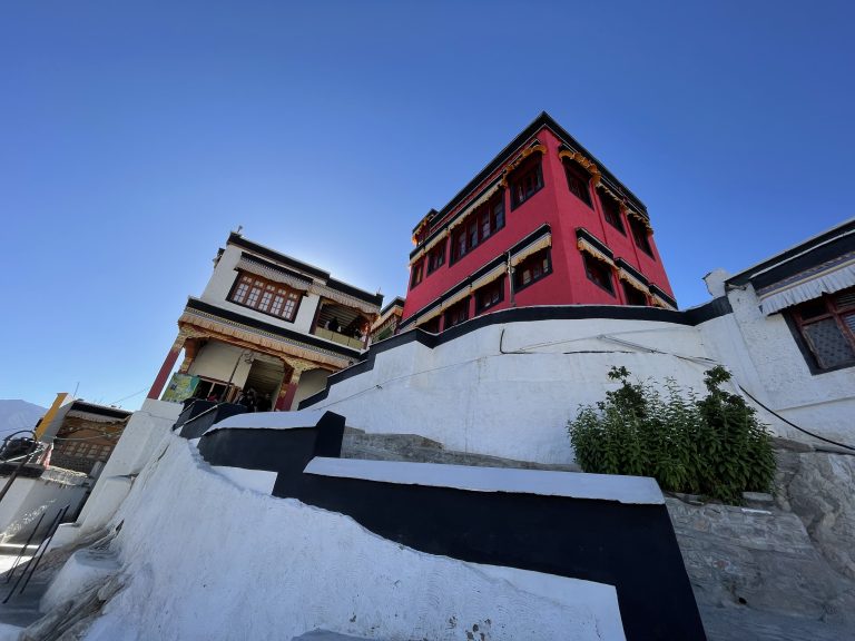 A red building with white walls and a black and white staircase situated on top of a hill.