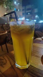 Orange Mojito served in a tall glass with black straw.

