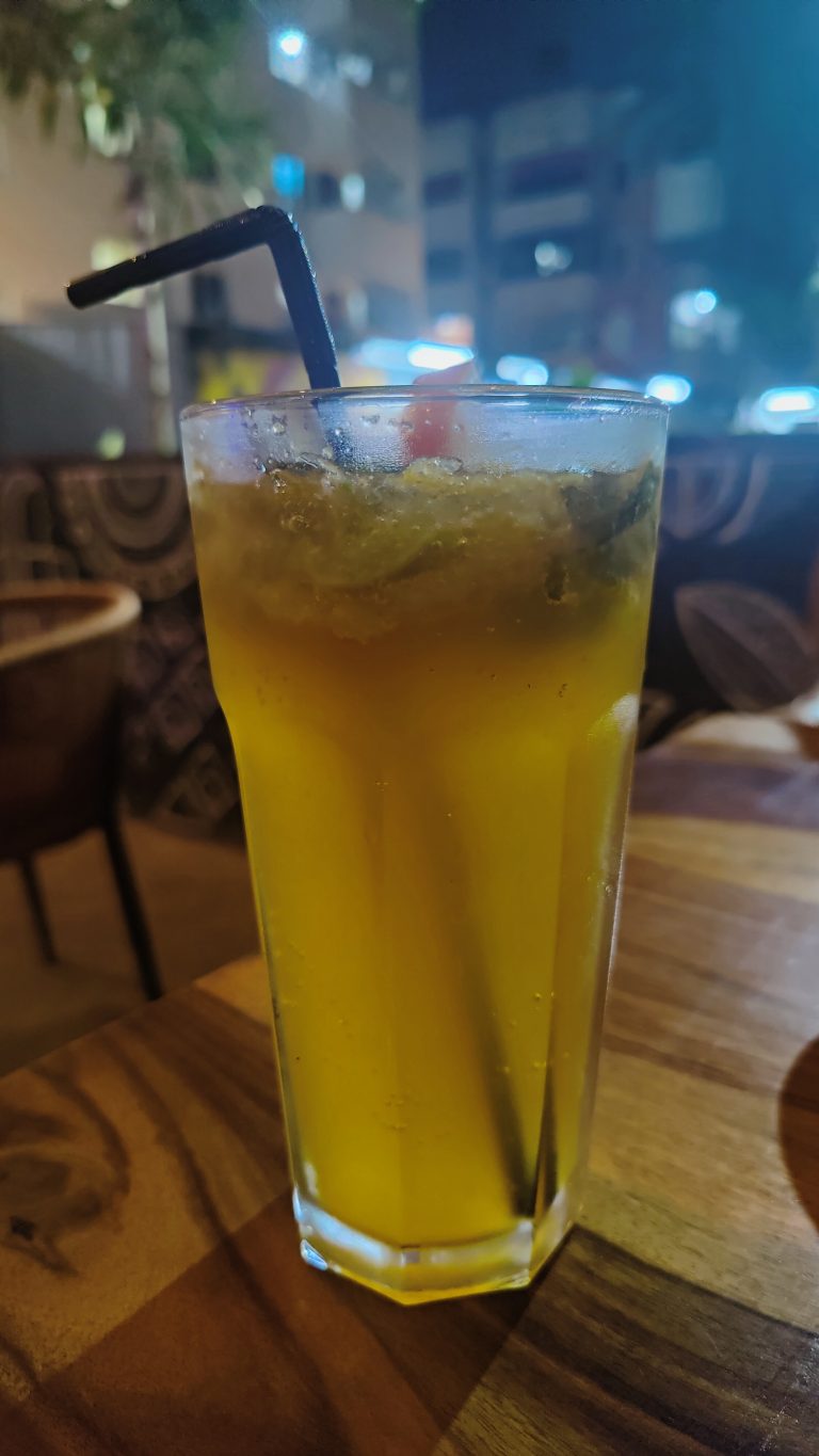 Orange Mojito served in a tall glass with black straw.