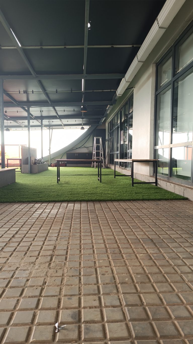 A ladder and tables and benches under an awning on green turf