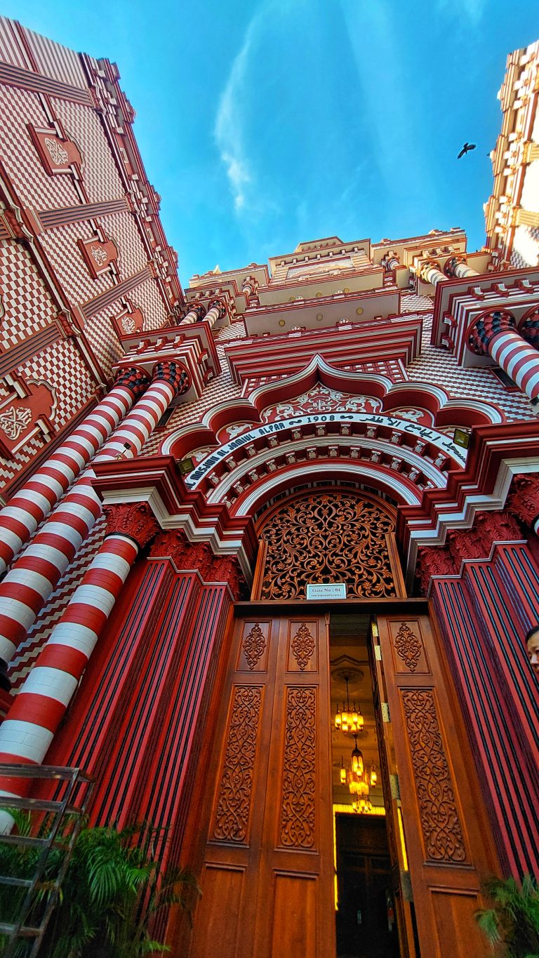 Gate 4 of the Jami Ul-Alfar mosque in Colombo, Sri Lanka. The style of architecture draws from a revivalist architectural style combining traditional Indo-Islamic architecture with more gothic with a red and white pattern (pomegranate) and new classical styles popular in the West.