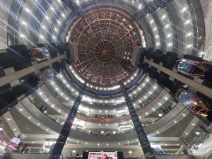 Looking up toward the ceiling of a shopping mall that has several levels 
