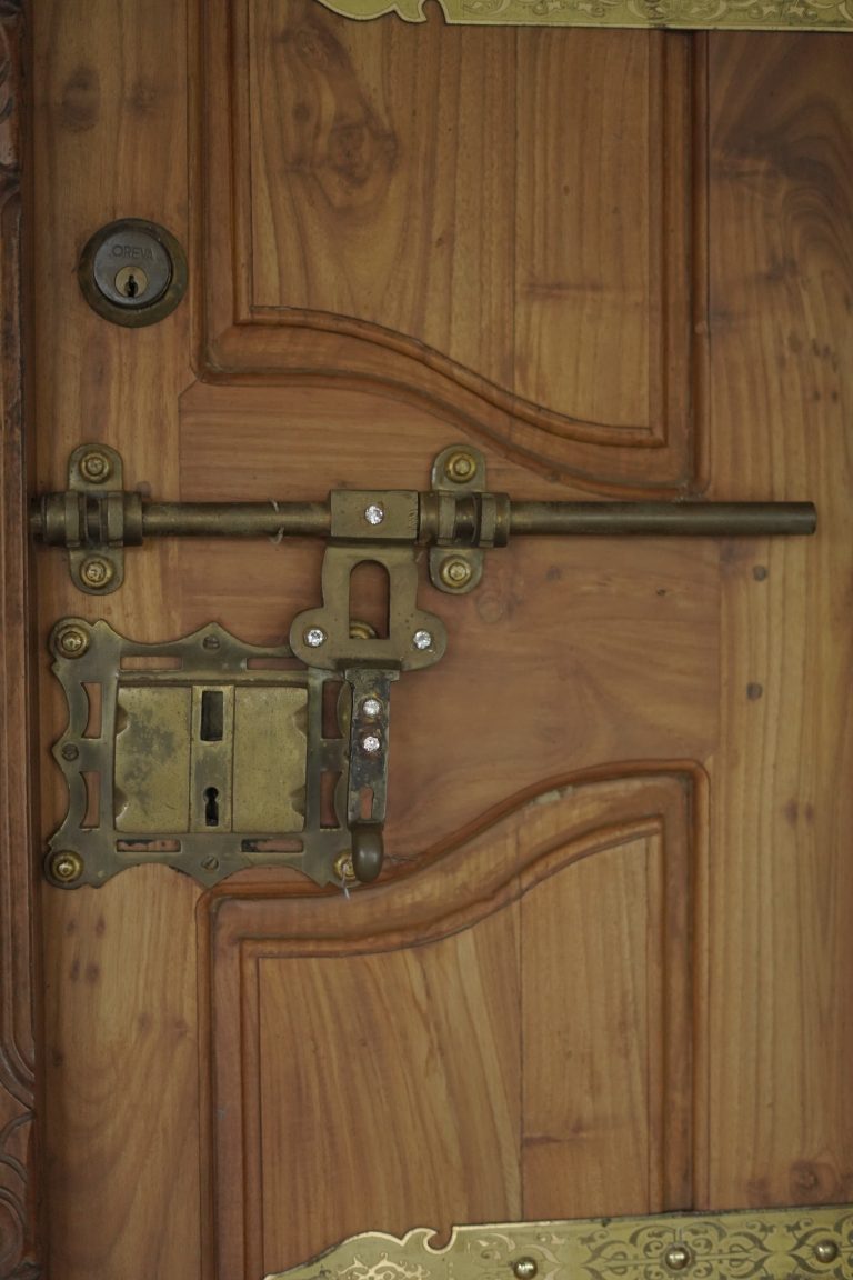 A traditional Kerala door lock on a wooden door.