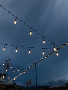 Under the captivating night sky, the rooftop glows with beautiful lights against the serene backdrop of the deep blue sky.