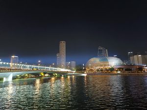 A beautifully lit river with a bridge and a cityscape in the background, showcasing Singapore’s Marina Bay area at night.
