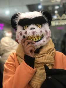 A person holds a scary panda mask in front of their face