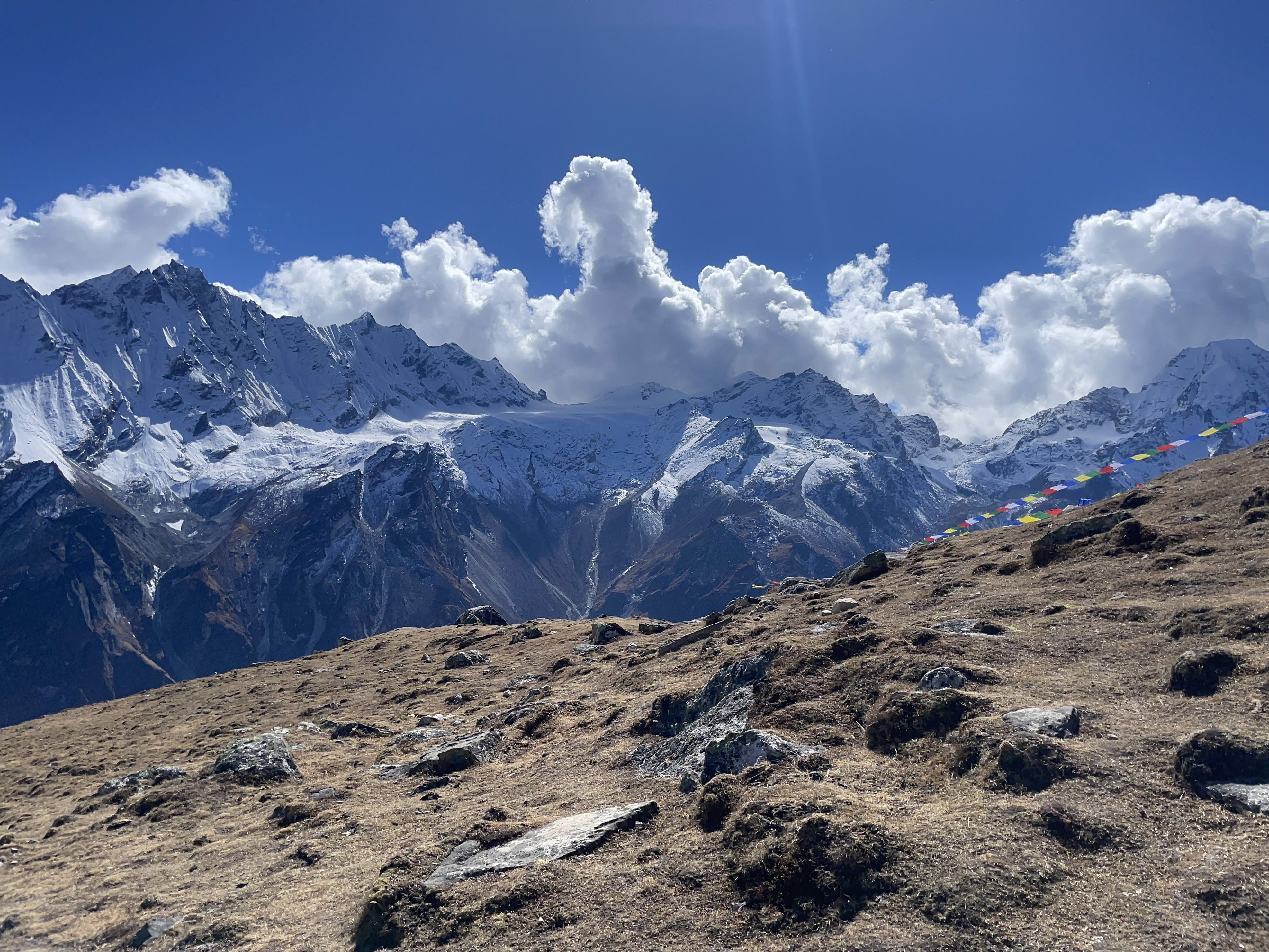 Langtang presents a stunning view of the Himalayas, with white clouds gracefully adorning the vivid blue sky.