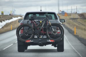 Suv car on the road with a bicycle attached to the back of it.
