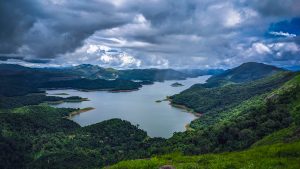 Mountain peaks surround a large body of water with dark thick clouds overhead