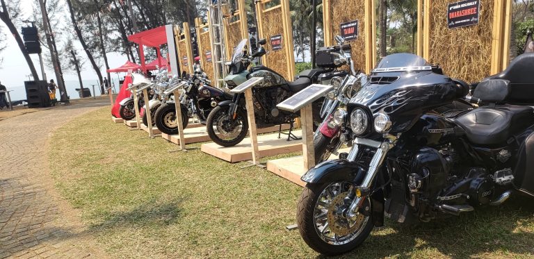 Motorcycles parked on a lawn near a cliff front beach.