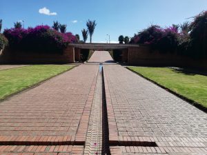 Brick road in Bogota with lawns and trees on both sides and an arch in the center.