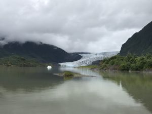 A view of the Mendenhall Glacier from the viewing are at the Mendenhall Glacier Visitor Center in Juneau, Alaska in July of 2017. The surrounding area is green with the glacier sticking out into the Mendenhall Lake.
