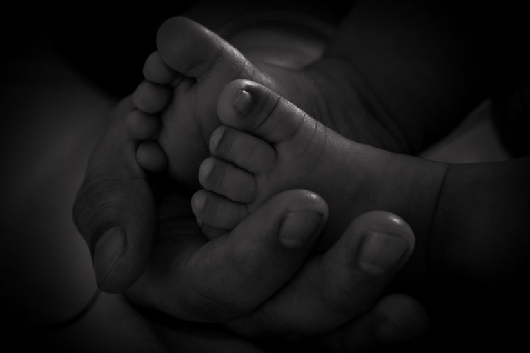 Tiny baby feet cradled delicately in the warmth of a mother’s hands.