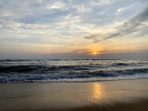 A view of sunset from the beach and the sky is partially cloudy.