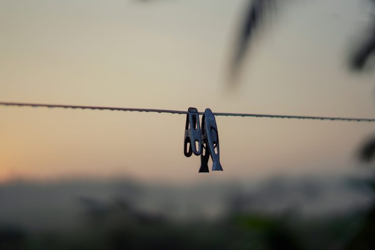 Pegs hanging on a rope outdoors.