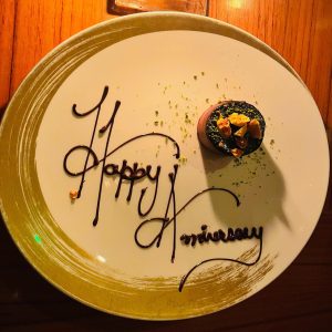  A plate with a chocolate cake topped with creamy frosting and chocolate shavings, for an anniversary celebration.