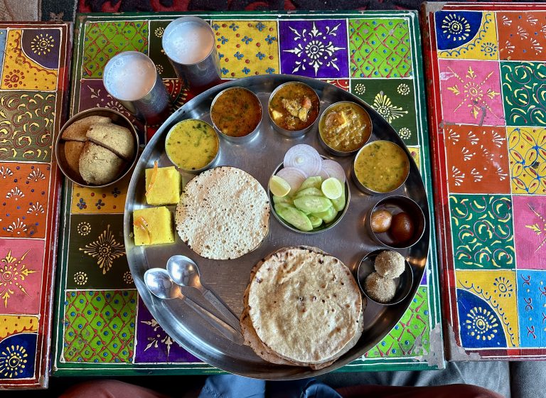 Colorful table with a plate of Rajsthani Dish Food Thali, showcasing a variety of delicious dishes.