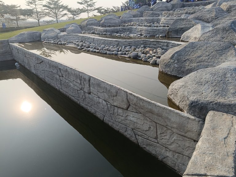 An artificial waterfall made and decorated by stones in a park.