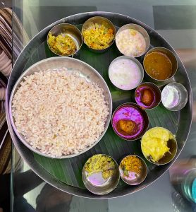 Kerala thali meals, with rice in a big bowl and different curries in small bowls.