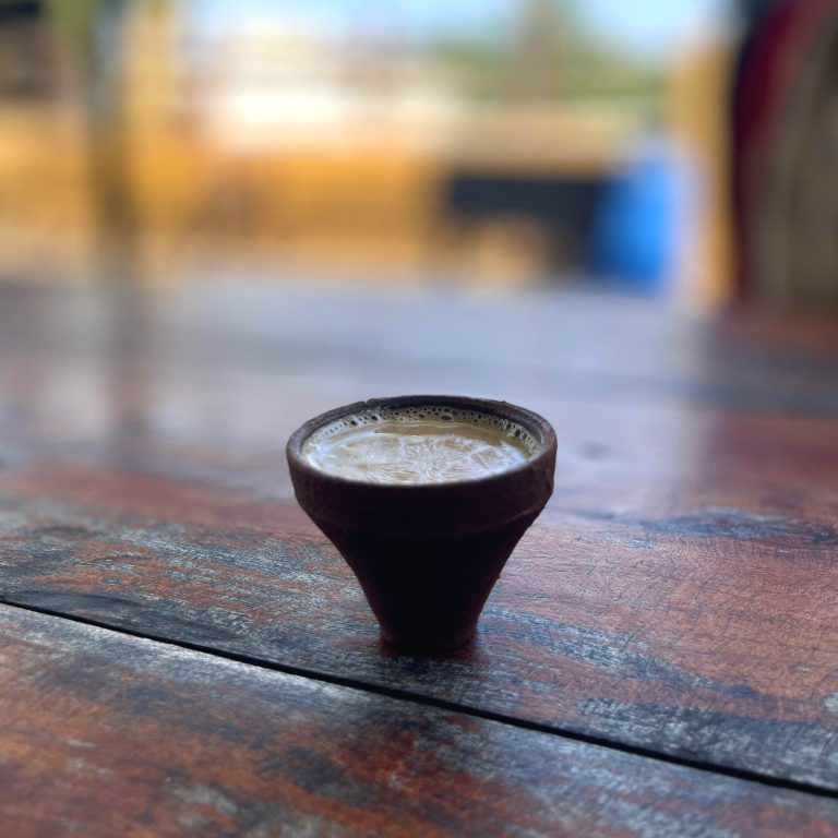 A cup of tea served on clay cup placed on a wooden table.