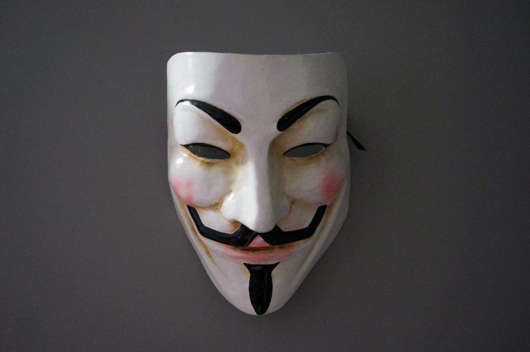 Guy Fawkes mask hanged in a grey wall.