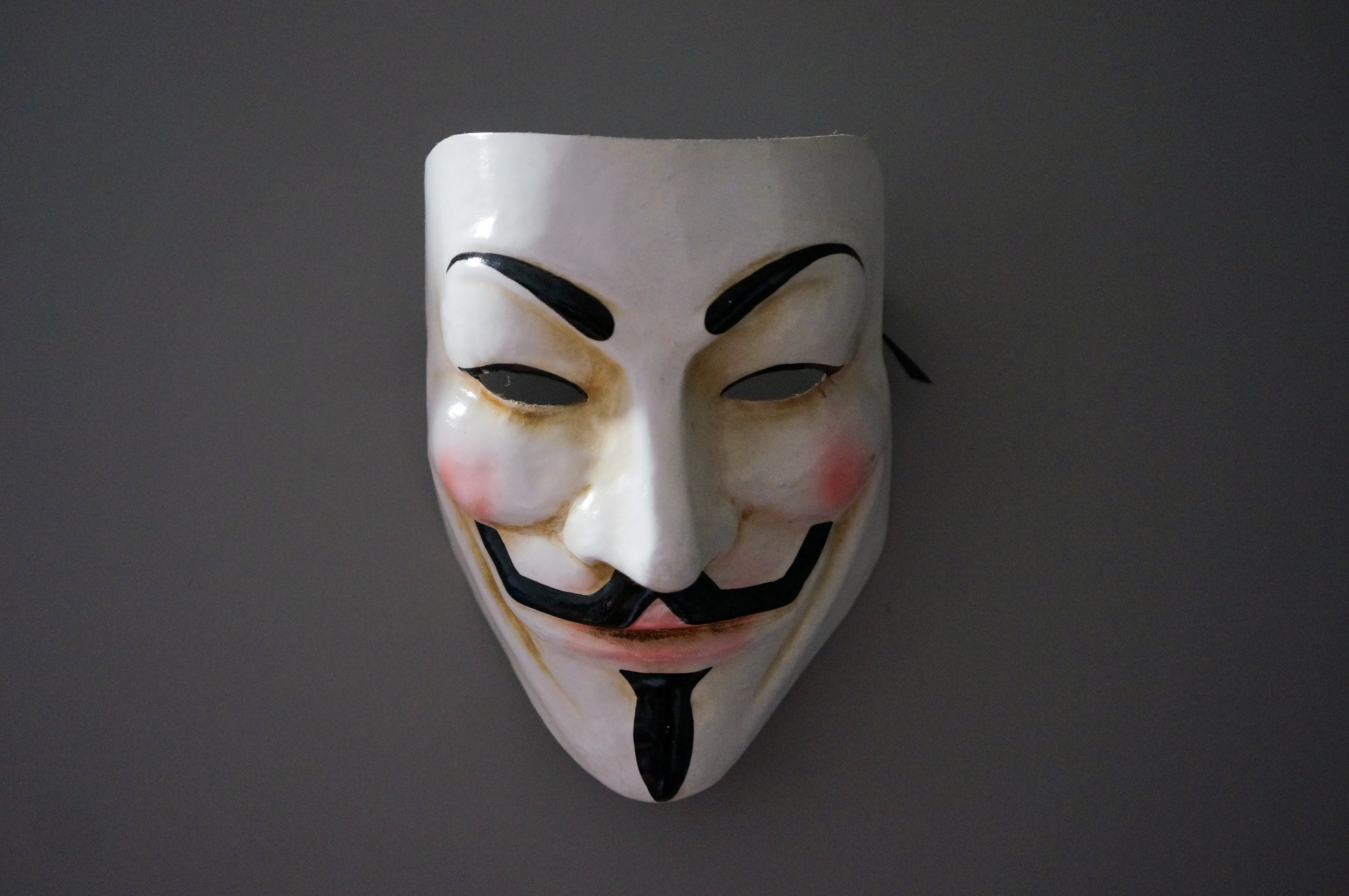 Guy Fawkes mask hanged in a grey wall. 