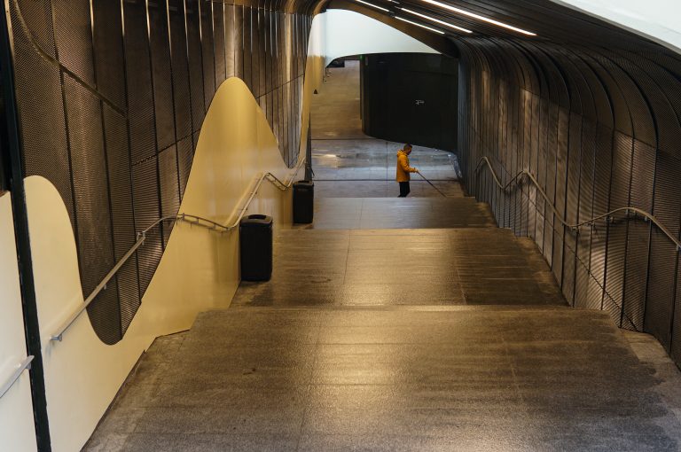 Maintenance worker mopping a very long flight of stairs wearing a yellow raincoat