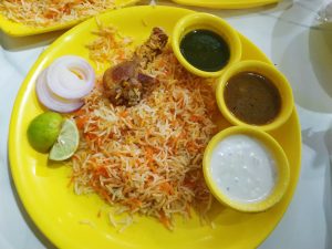 Delicious Biryani rice and sauce on a yellow plate.