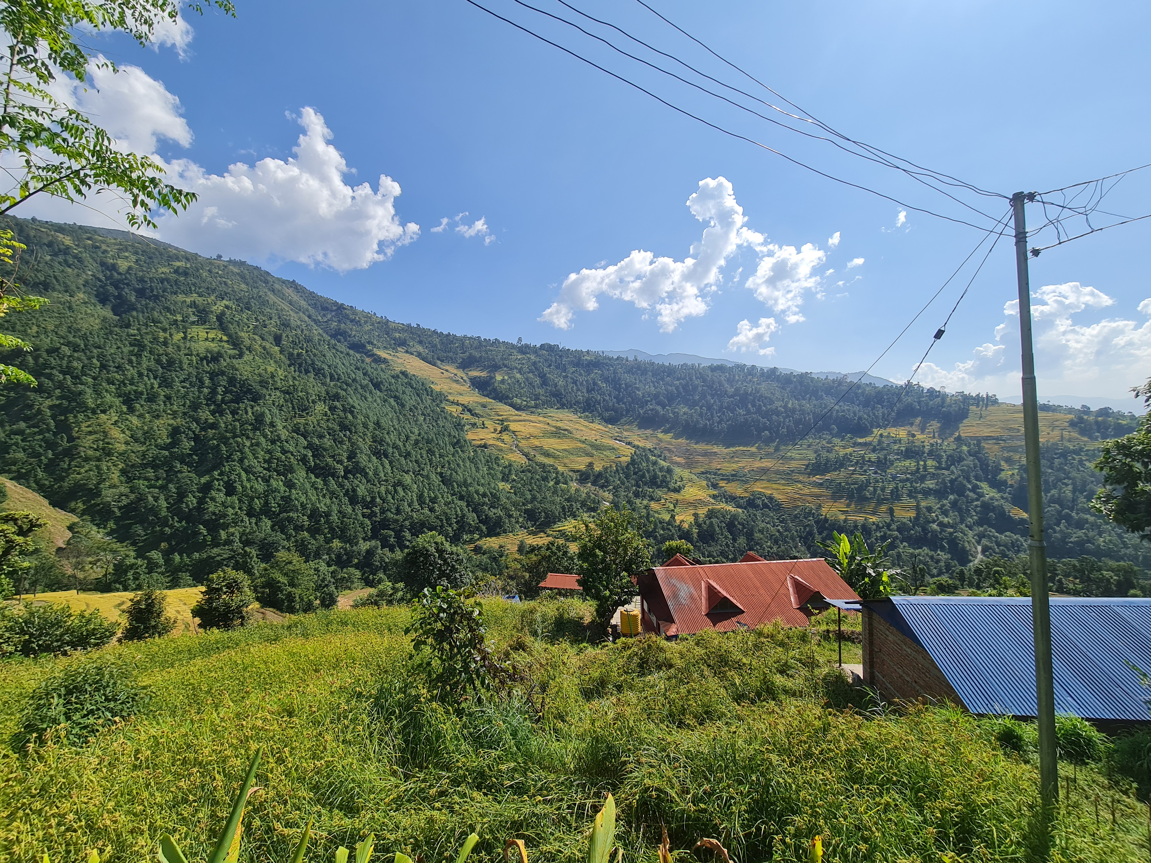 Mountainous terrain covered in greenery beneath a sky filled with clouds.