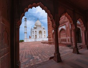 Side view of Taj Mahal through an arch of a brown building, Agra.