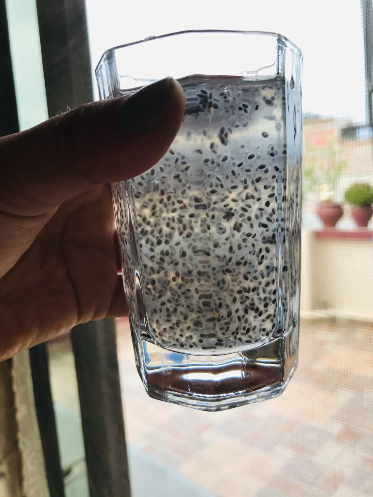 Chia seed drink in a glass, held in front of a window