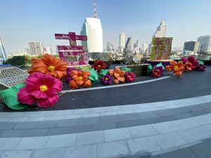 Some artificial giant colorful flowers and multi level buildings in behind 
