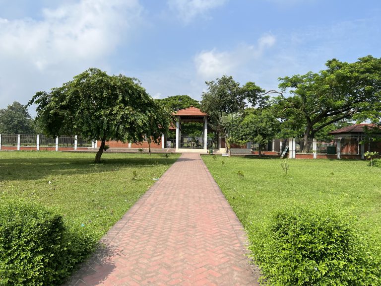 A brick path leading to a building surrounded by trees and grass.