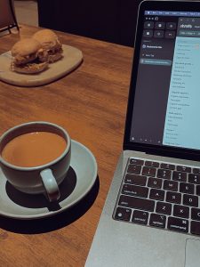A cup of coffee, a laptop, and a burger.

