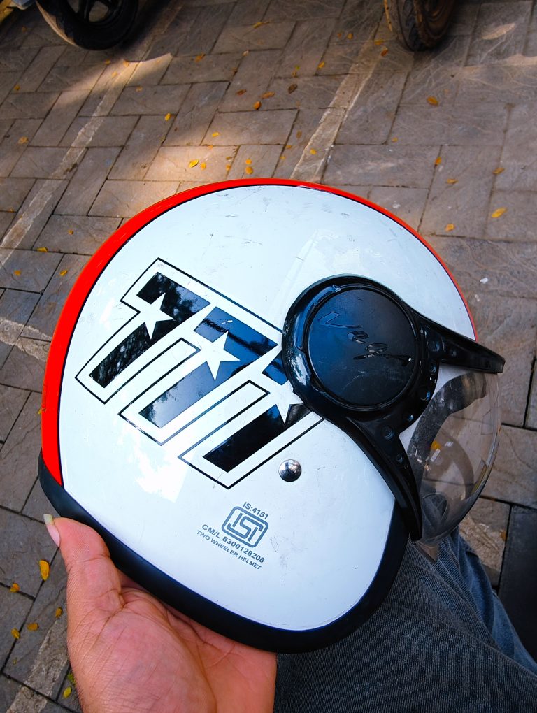 A hand holding a white and red coloured helmet.