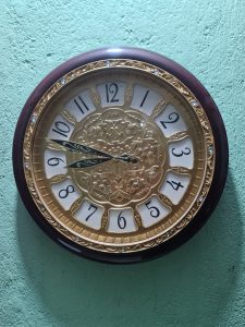 View larger photo: A circle-shaped watch featuring brown, golden, and white colors is displayed on a green wall.