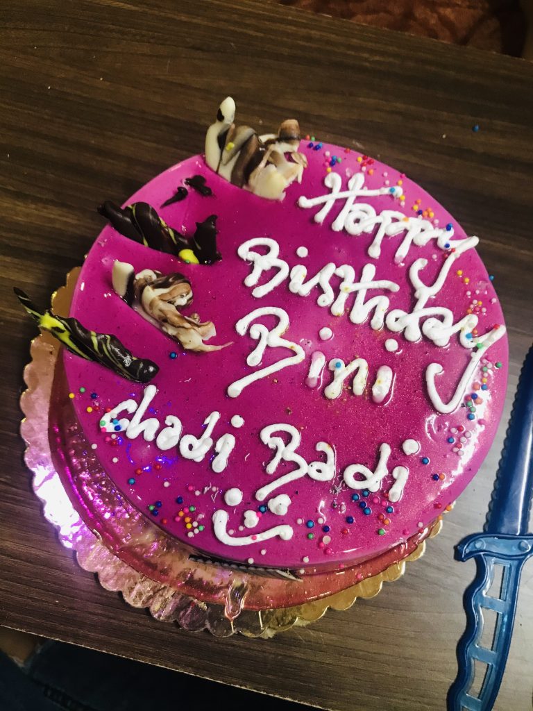 A pink violet cake with a white birthday message.