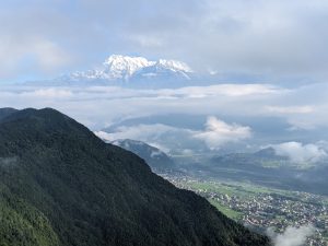 View larger photo: Sarangkot, Pokhara, Nepal in the valley between a green mountain at the forefront, and a snow-covered mountain in the background.