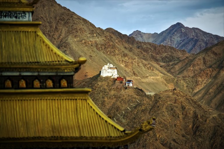 View of Mountain range and white and red colored buildings on one of the cliffs. Tsemo Gompa view from Leh Shanti Stupa located in Leh,ladakh.