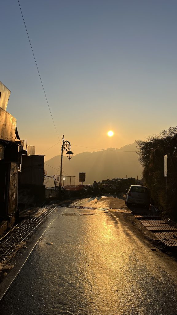 Sunset’s warm glow, charming street view, picturesque hill station ambiance.