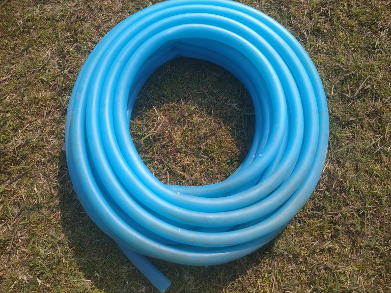 A roll of blue garden hose on the lawn. Let your garden thrive with gentle tough of a watering pipe.