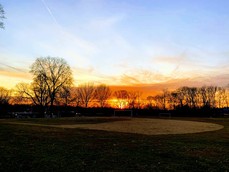 Sunset behind leaf-less trees, soccer goals, and a baseball field (Towson, Maryland)