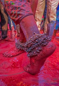 Colorful legs adorned with anklets, dancing in the vibrant hues of Holi celebration.