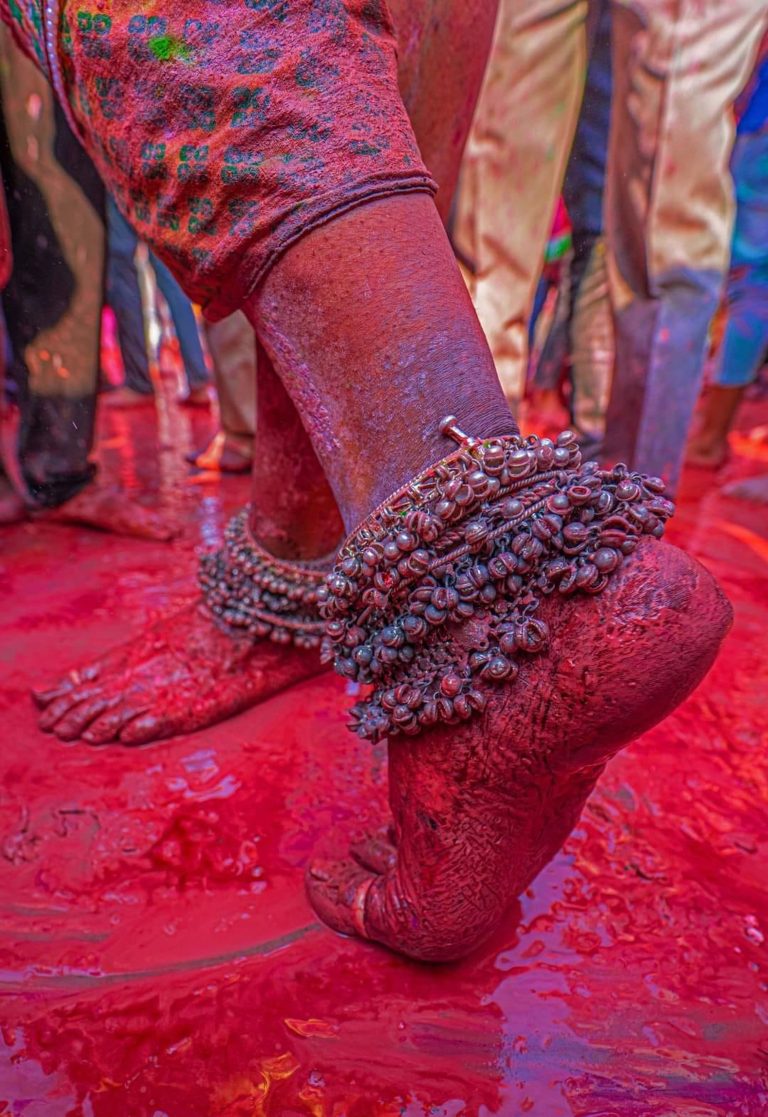 Colorful legs adorned with anklets, dancing in the vibrant hues of Holi celebration.