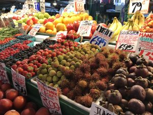 A colorful fruit stand inside Pike Place Market in Seattle, Washington featuring various berry and apple varieties, bananas, nectarines, and rambutan.
