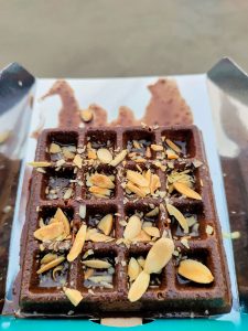 A delicious waffle topped with sliced almonds and drizzled with rich chocolate.
