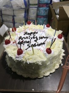 Circular white anniversary cake adorned with unlit candles.