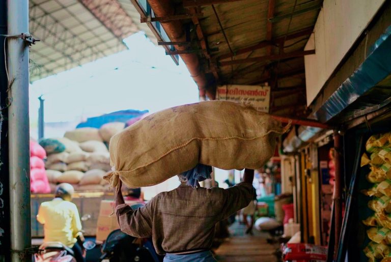 A hardworking man is walking with a sack on his head.