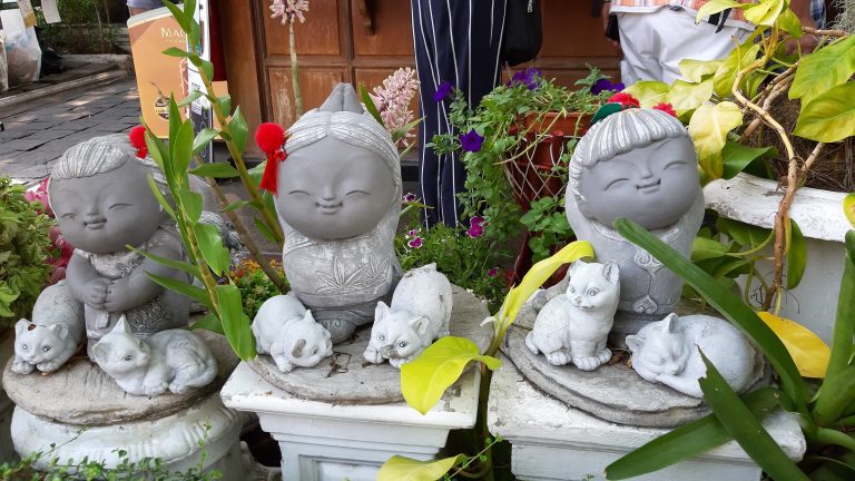 A group of stone statues of girls sitting next to each other.